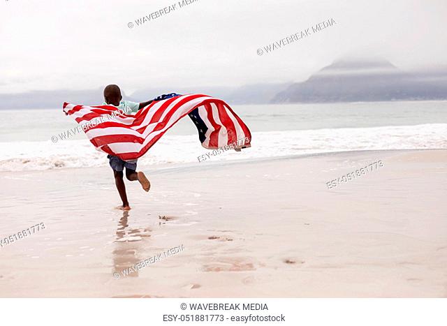 Boy running with American flag on the beach