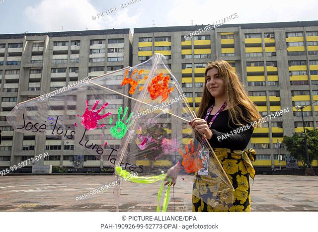 26 September 2019, Mexico, Mexiko-Stadt: A young woman raises a dragon with the number 43, the name of a disappeared student teacher