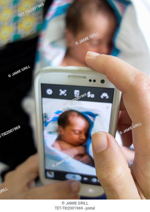 Mother photographing newborn daughter