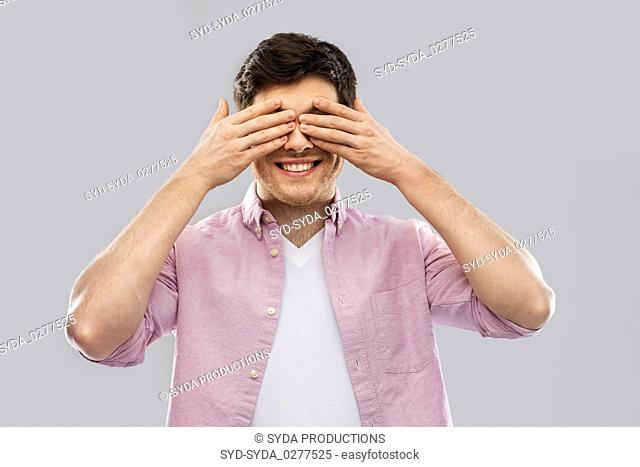 man closing his eyes by hands over grey background