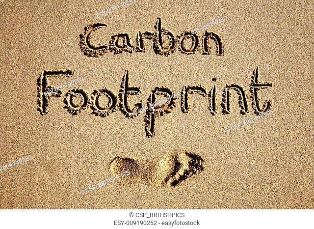 Carbon footprint written in sand on a beach