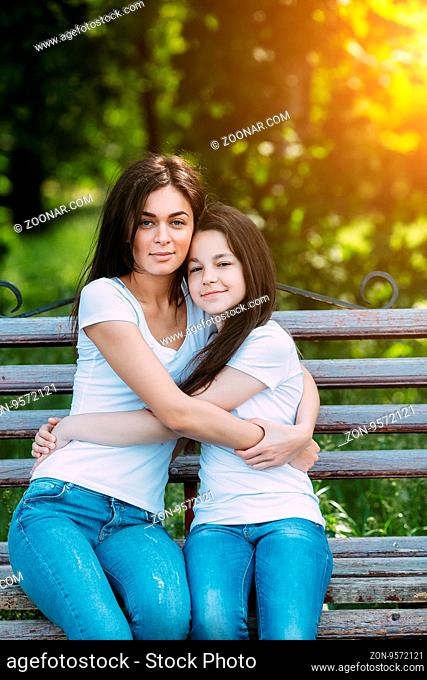 Mother and daughter sitting on a bench in the park