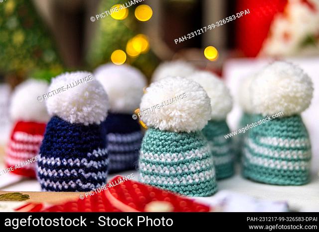 16 December 2023, Brandenburg, Leuthen: Egg warmers in the shape of bobble hats lie on a stall at a small Advent market. Advent and Christmas markets are also...