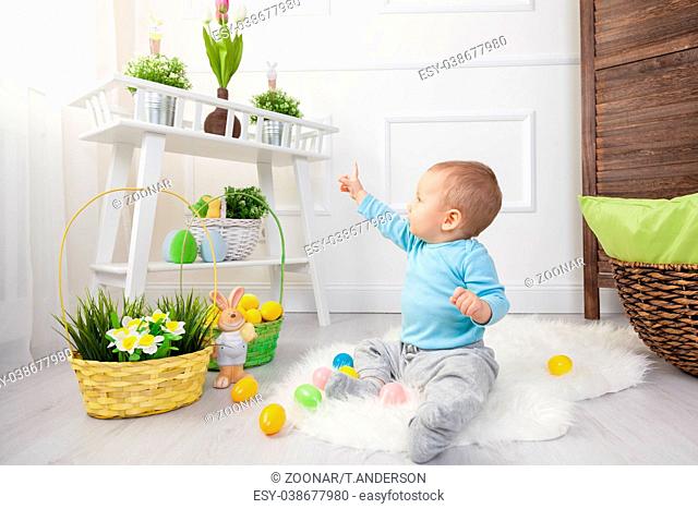 Easter egg hunt. Adorable child playing with colorful Easter eggs at home