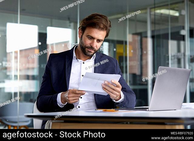 Businessman examining document while sitting in office