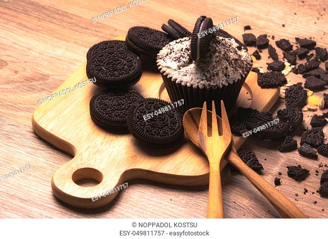 Chocolate cupcake and cookies are on wooden plate