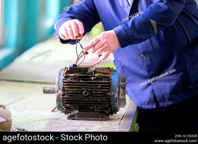 Worker's hands make an old electric motor