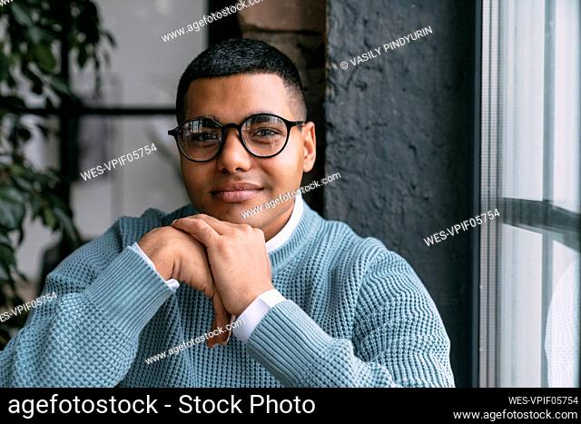 Young man wearing eyeglasses by window at home