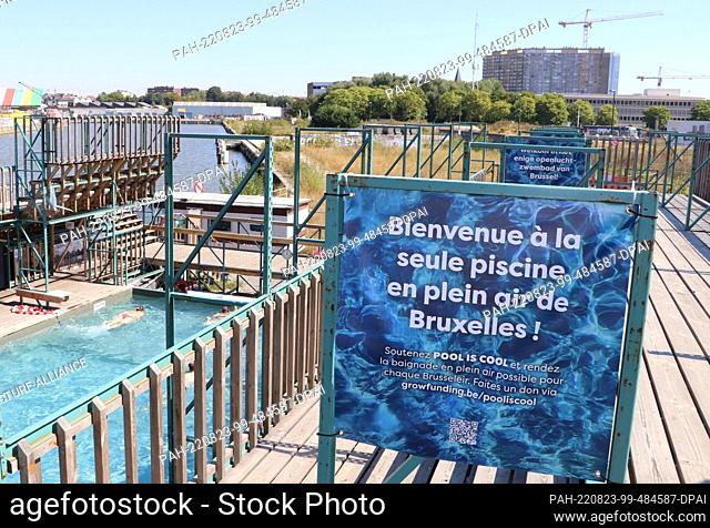 12 August 2022, Belgium, Brüssel: A sign with the French inscription ""Welcome to the only open-air swimming pool in Brussels"" stands on a terrace of the...