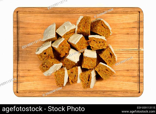 Top view glazed mini pieces of carrot cake on wooden plate isolated over white background
