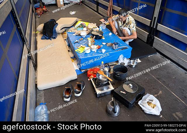 13 September 2023, Hesse, Gräfenhausen: A truck driver from Tajikistan sits in the parking lot of the Gräfenhausen service area at a makeshift dining table on...