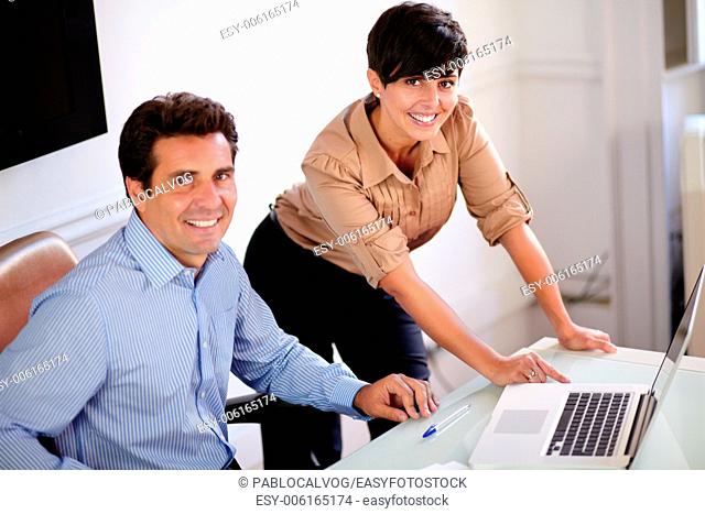 Portrait of a businessman and businesswoman looking at you while smiling at the office