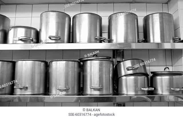 Stainless steel cooking pots on kitchen shelves