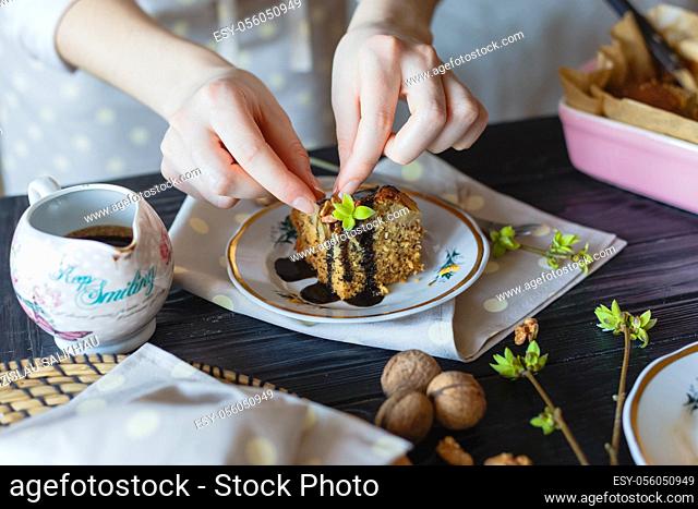 The housewife decorates a piece of cake with walnuts