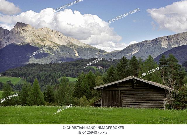 Wooden hut on a meadow behind the mountain range Rosengarten, Deutschnofen, Eggen valley, South Tyrol, Italy