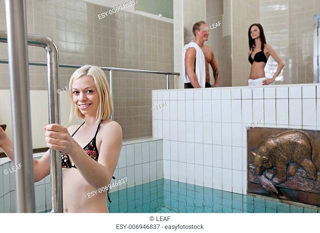 Portrait of pretty blond girl in the pool with people in background