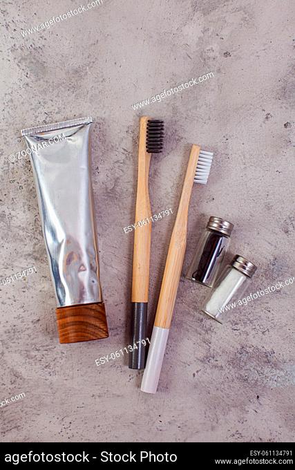 Natural eco-friendly bamboo toothbrushes with white and black bristles, tube of eco toothpaste, bottles with dental floss. Family set for dental care