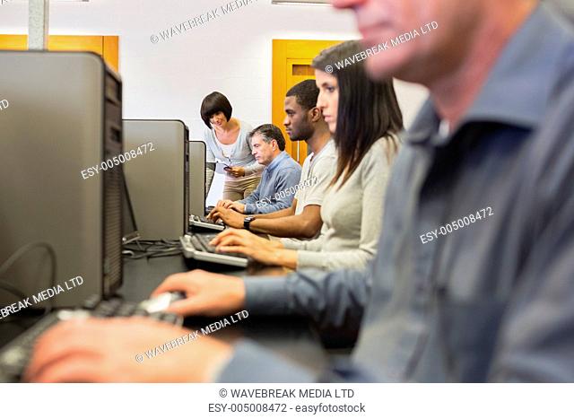 Teacher helping her students in computer class in college
