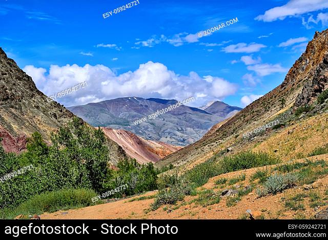 Picturesque summer mountain landscape - view from the canyon of Kyzyl Chin with multicolored clay cliffs to the Kuray Range, Altai mountains, Russia