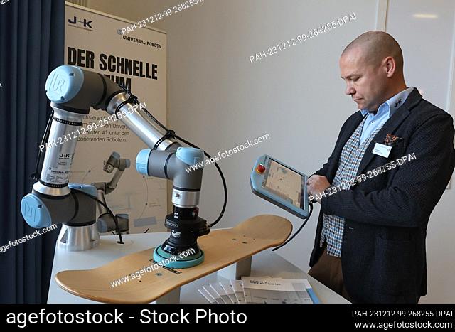 12 December 2023, Thuringia, Erfurt: Christian Held from Jugard+Künstner works on a robot grinding machine at the launch event of the Competence Center for...