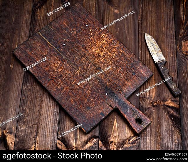 very old empty kitchen cutting board with holder and knife on a brown table, top view