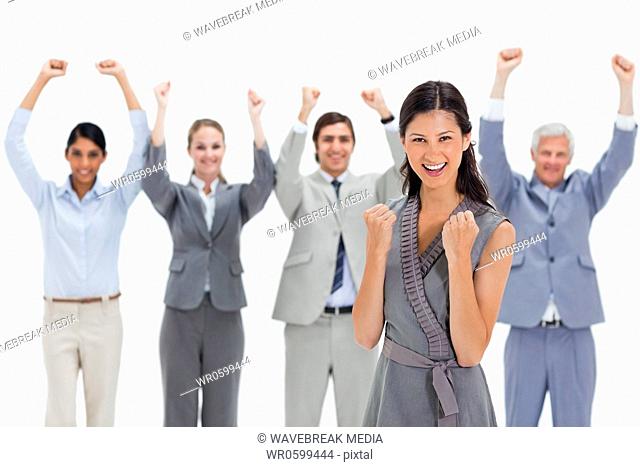 Close-up of a smiling woman clenching her fists with a business team raising their arms