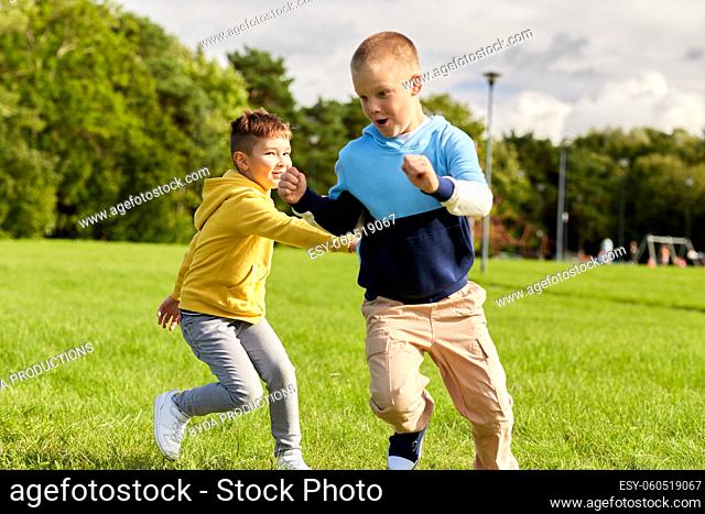 two happy boys playing tag game at park