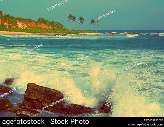 Large ocean waves breaking on the rocks of tropical coast - vintage retro style