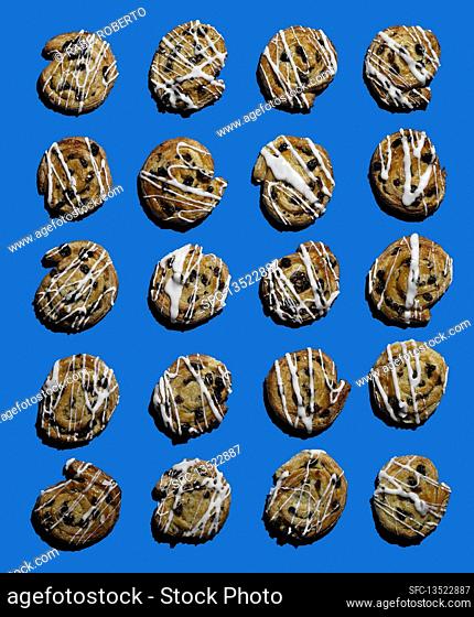 Multiple raisin buns on a blue surface