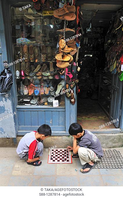 Children playing chess in front of the shop