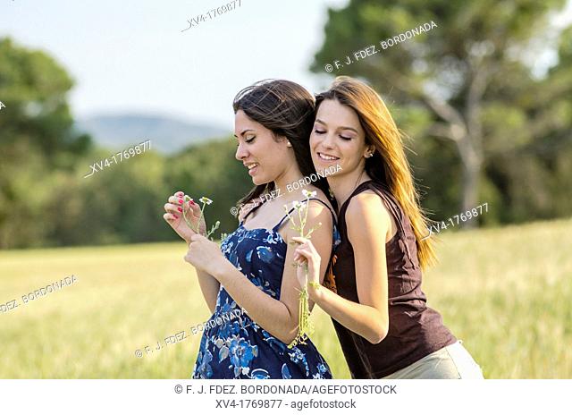Couple of girls playing and enjoyment whit flowers in the countryside