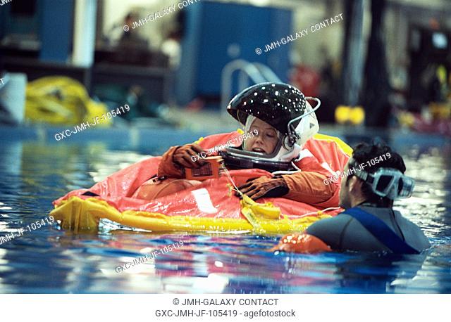 Astronaut Pamela A. Melroy, STS-112 pilot, assisted by divers, floats in a small life raft during an emergency egress training session in the Neutral Buoyancy...