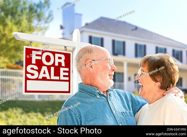 Happy Senior Couple Front of For Sale Real Estate Sign and House
