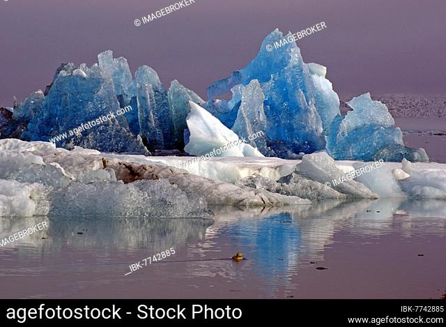 Blue iceberg reflected in the water, ice edge rising out of the mist, Jökulsarlon, glacier lagoon, Scandinavia, Iceland, Europe
