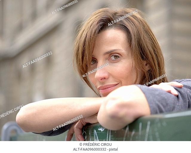 Woman leaning against railing outdoors, portrait