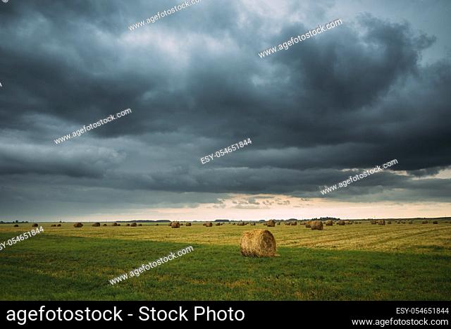 Dramatic Sky Before Rain With Rain Clouds On Horizon Above Rural Landscape Field Meadow With Hay Bales After Harvest. Agricultural And Weather Forecast Concept
