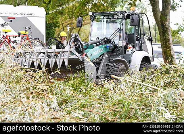 25 August 2023, Bavaria, Lindau: Workers use a wheel loader to remove trees and branches from a campsite. The previous night