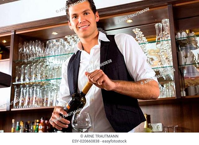 Barmann steht hinter Bar mit Wein