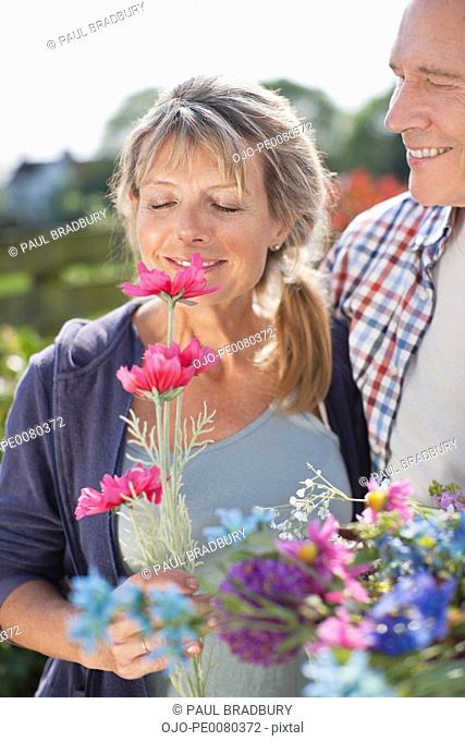 Senior couple smelling flowers in garden