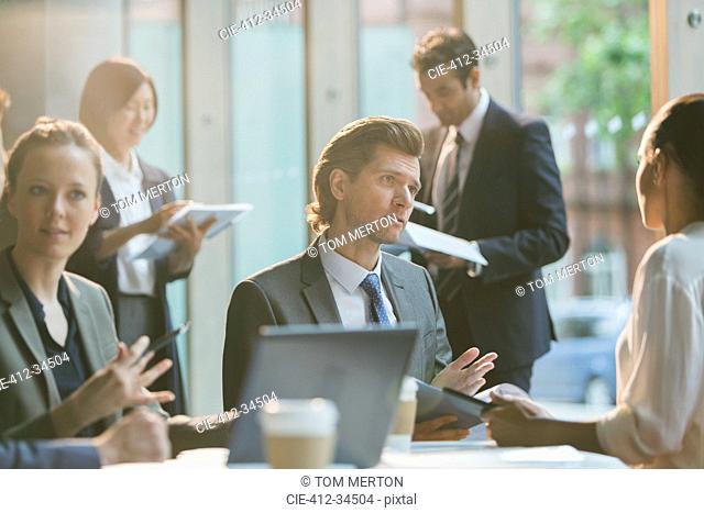 Serious businessman talking to businesswoman in conference room meeting