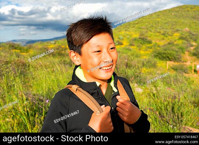 Young sporty Asian boy enjoying and hiking the mountain during the California Golden Poppy and Goldfields blooming in Walker Canyon, California. USA