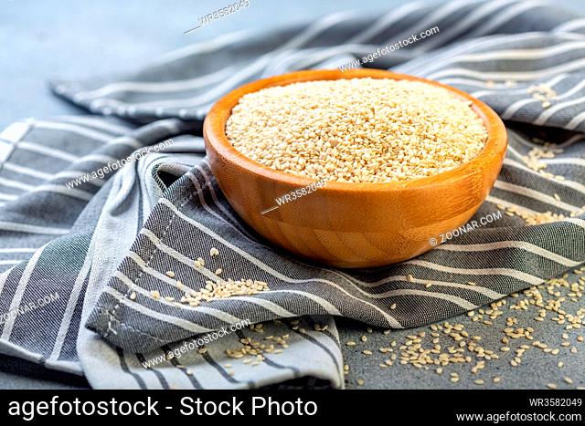 Bowl with sesame seeds on linen cloth, selective focus