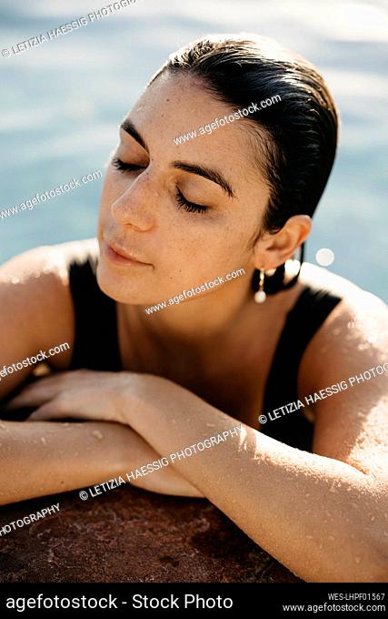 Woman with wet hair relaxing at poolside