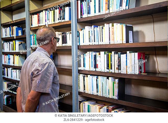 The famous national library of Fort de France in Martinique, retired caucasian man bold looking at all the books and exhibit in the library