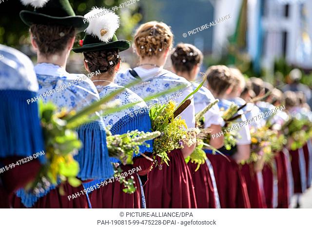 15 August 2019, Bavaria, Kochel Am See: Women dressed in traditional costumes with herb bushes take part in the traditional costume procession through the...