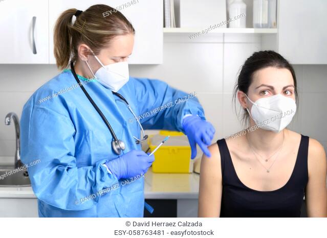 Young woman with protective face mask getting vaccinated, coronavirus concept. High quality photo