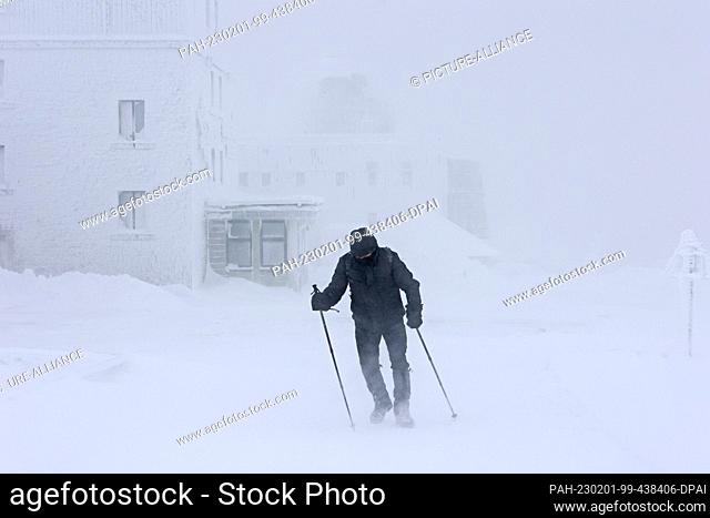 PRODUCTION - 01 February 2023, Saxony-Anhalt, Schierke: A hiker walks along the Brocken in a snowstorm. Heavy storms with snow and freezing rain again prevented...