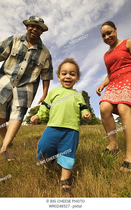 A couple playing with their son in a grassy field