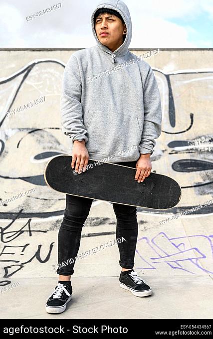 Young skater posing with skateboard at skate park