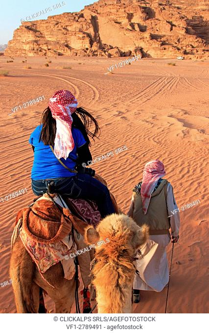 Tourist riding a camel at sunset in the Wadi Rum desert, Jordan